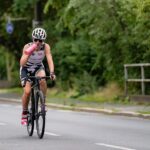 Cycliste casqué en plein effort sur une route, bidon d'eau à la main
