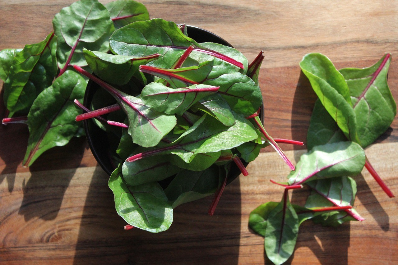 Feuilles de blettes fraîches, un légume source de spermidine, posées sur une planche en bois