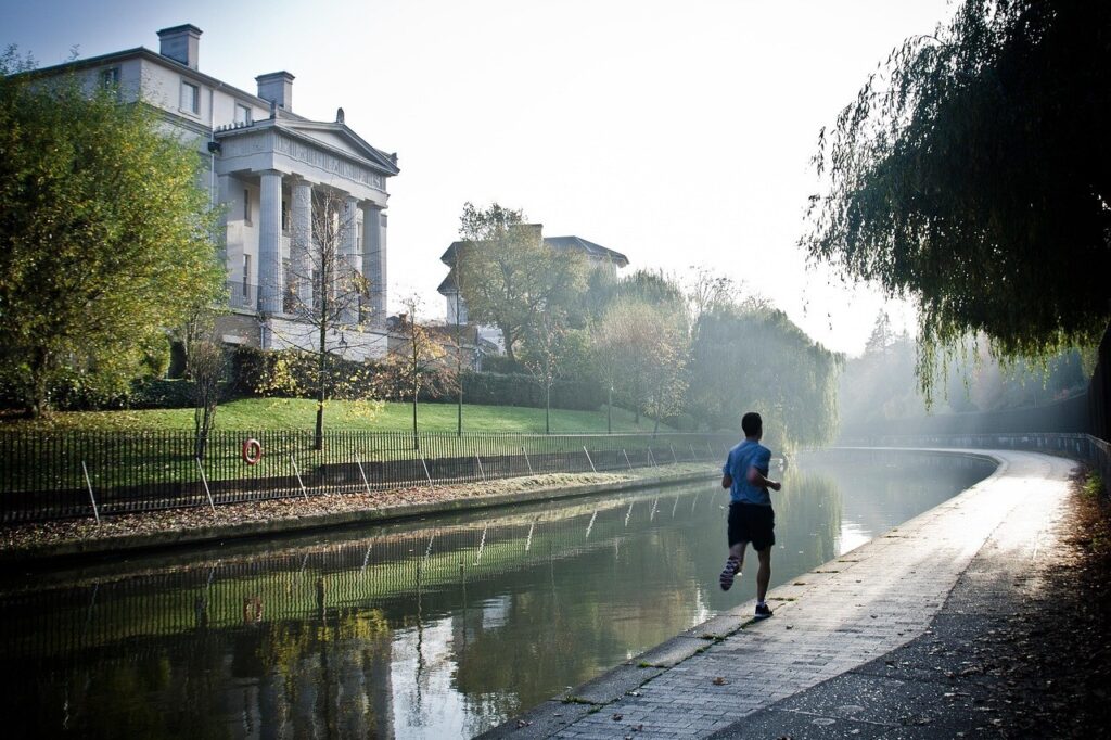 Coureur seul en foulée régulière le long d'un canal, tôt le matin