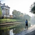 Coureur seul en foulée régulière le long d'un canal, tôt le matin