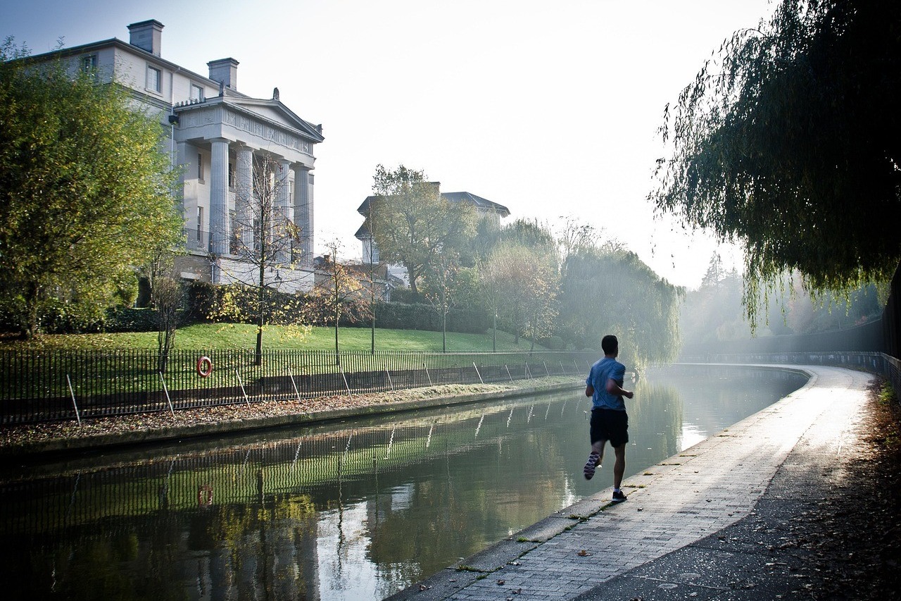Homme courant seul le long d'un canal un matin brumeux, scène ordinaire et candide