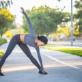 Femme s'étirant dynamiquement sur un chemin de parc avant une sortie sportive