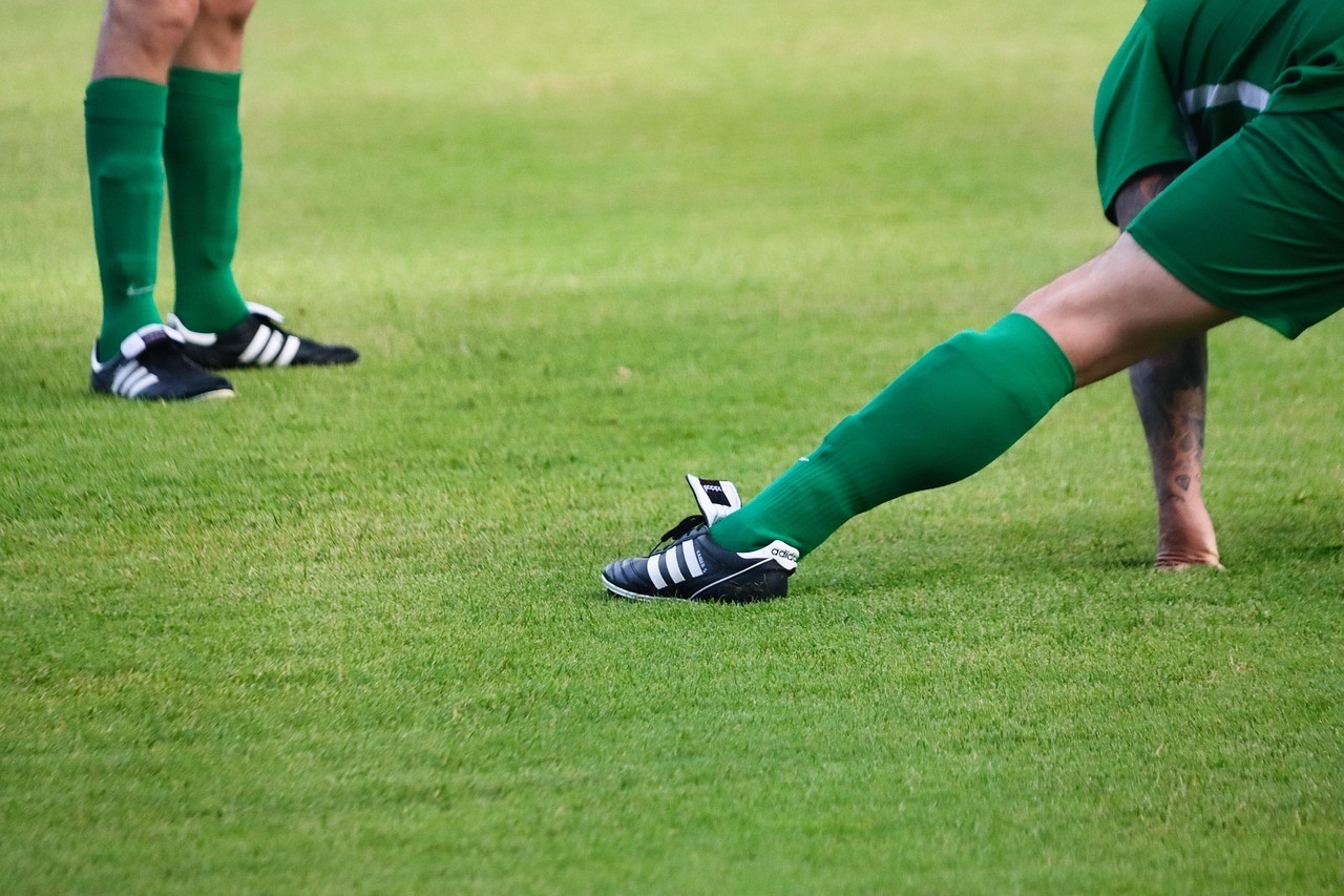 Joueurs de football amateurs étirant le mollet sur un terrain d'entraînement avant un match