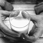 Mains tenant un verre de lait, photo candide en noir et blanc