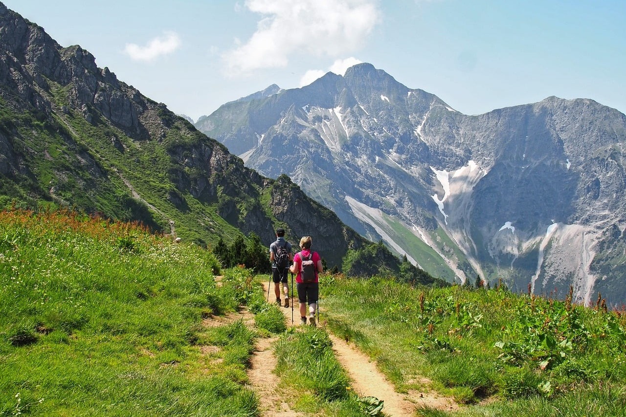 Deux personnes progressent avec des bâtons de marche sur un sentier de montagne, en plein effort d'endurance