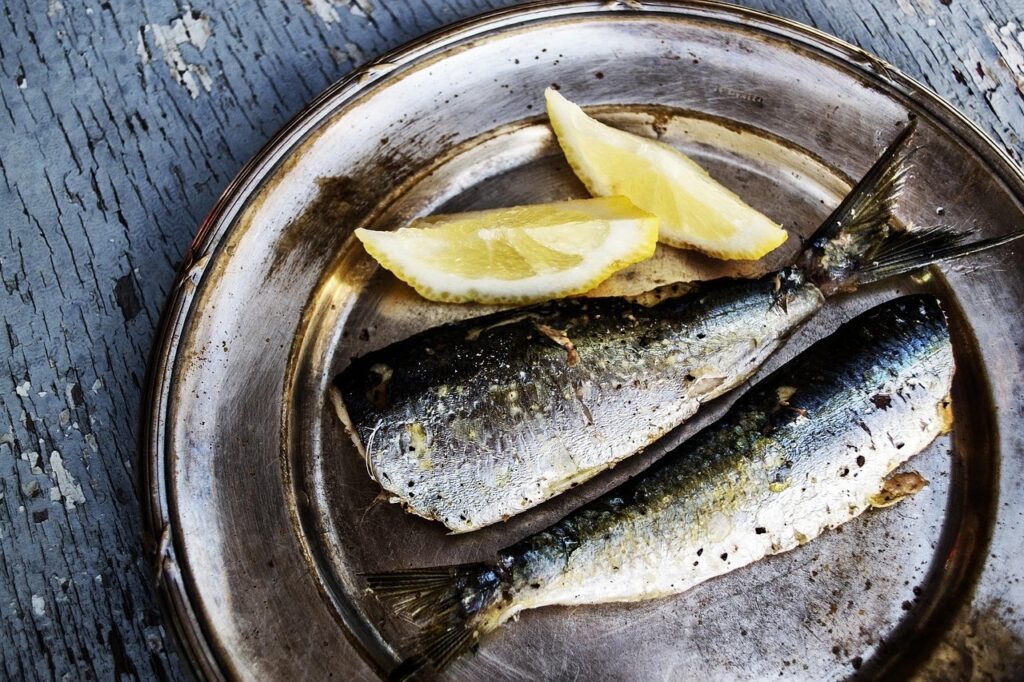 Sardines grillées sur une assiette avec quartiers de citron