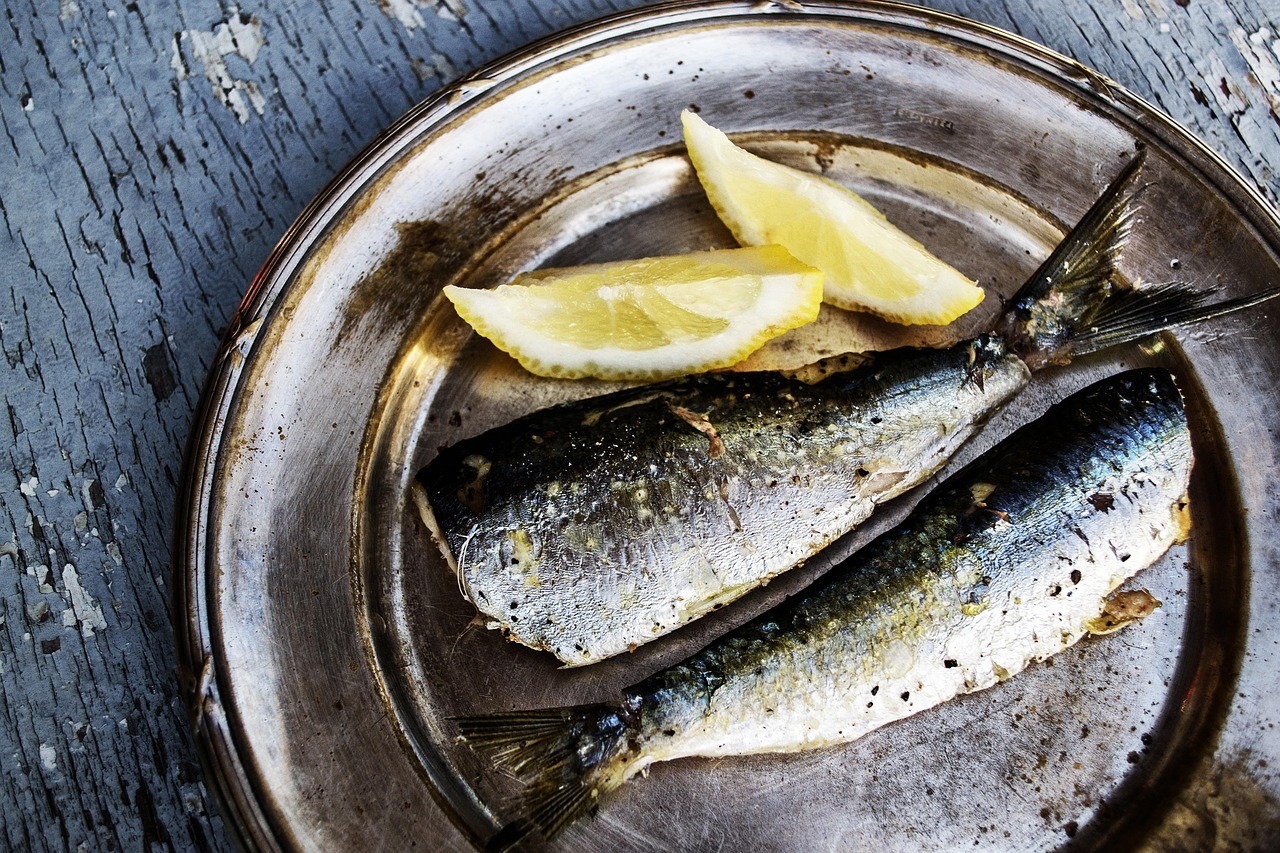 Sardines grillées sur une assiette avec quartiers de citron