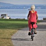 Femme senior faisant du vélo au bord d'un lac, vue de dos