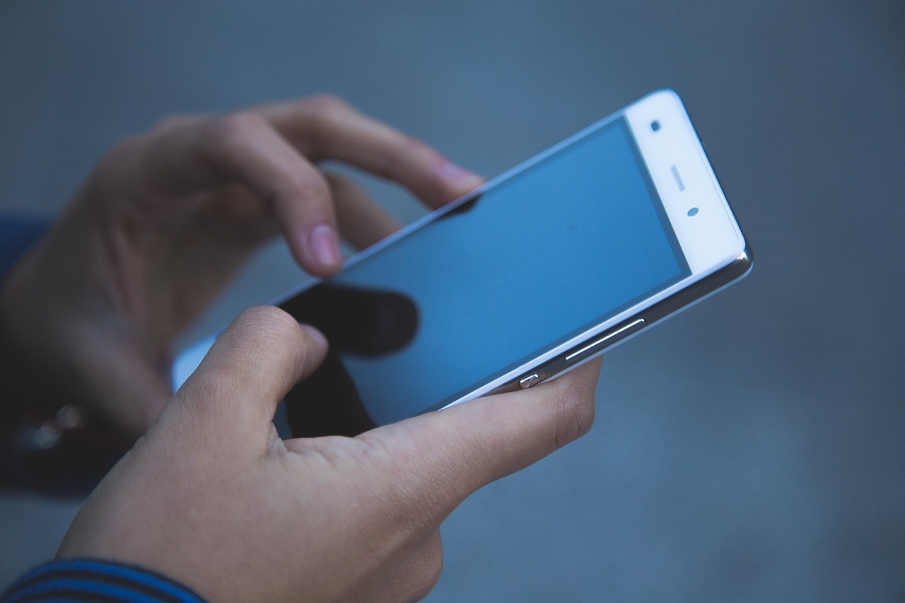 Mains tenant un smartphone, scrolling candide sur les réseaux sociaux