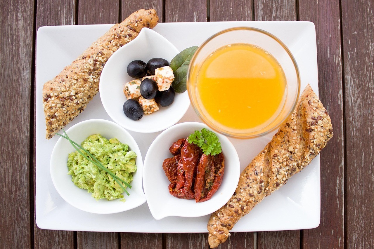 Plateau de petit-déjeuner varié avec jus d'orange, pain et crudités